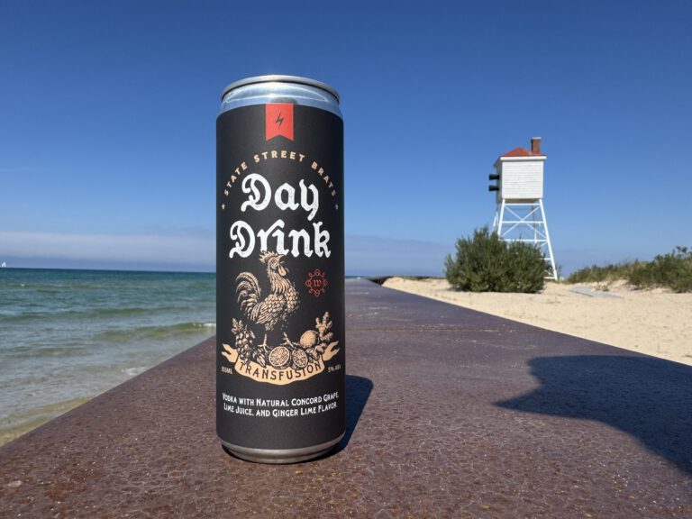 A Day Drink in hand on the lakeshore, a lighthouse in the background.
